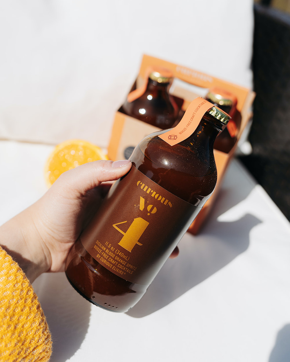 A hand holds a bottle of Curious No. 4 in the sun. 