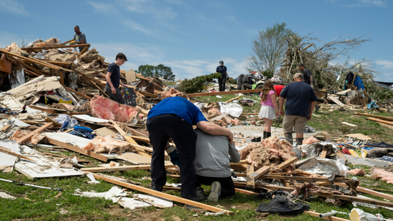 A couple hold each other amid destruction from a storm.