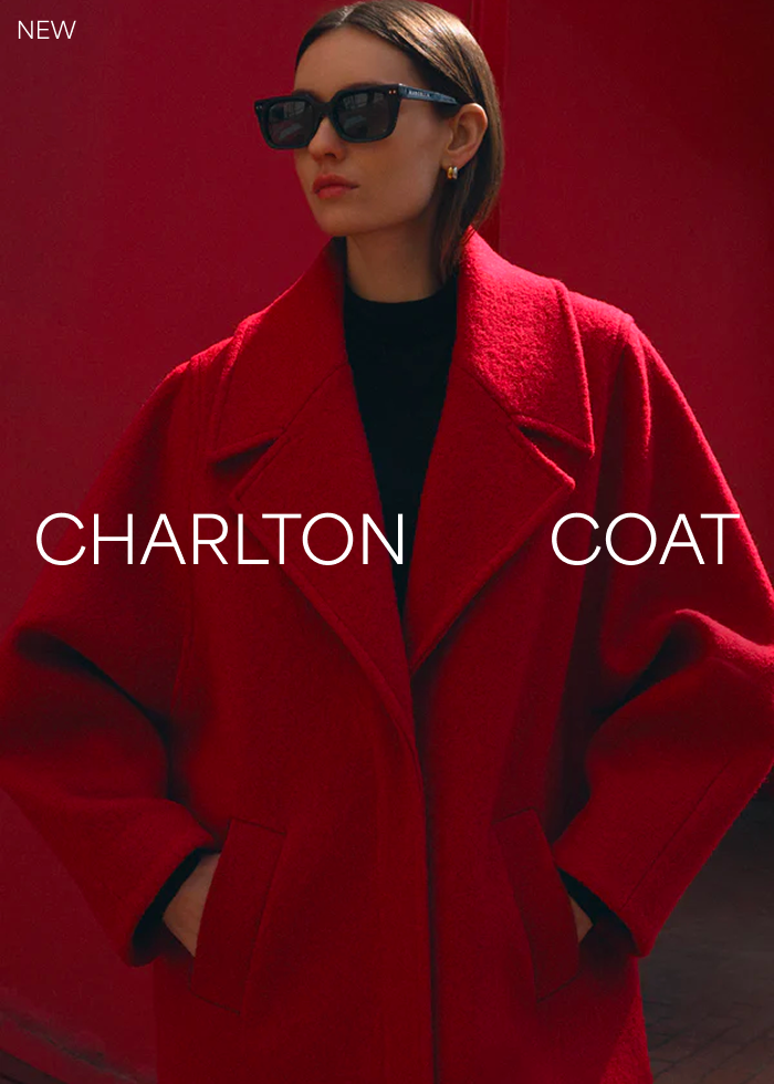 Fred in The Charlton Coat and sunglasses poses against a red background with the text “Charlton Coat.”