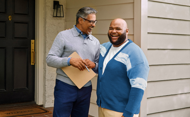Real estate agent and potential buyer talking on a front porch.