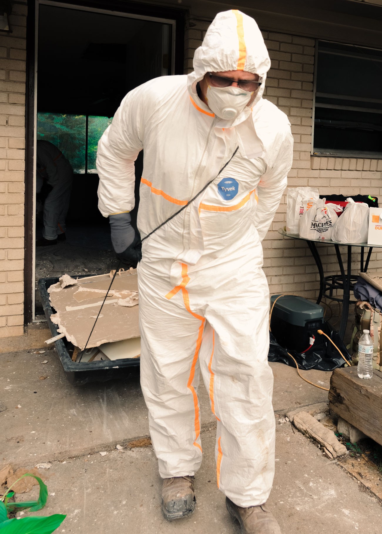 A Team Rubicon Greyshirt in protective gear mucks out flood-damaged property in Texas.