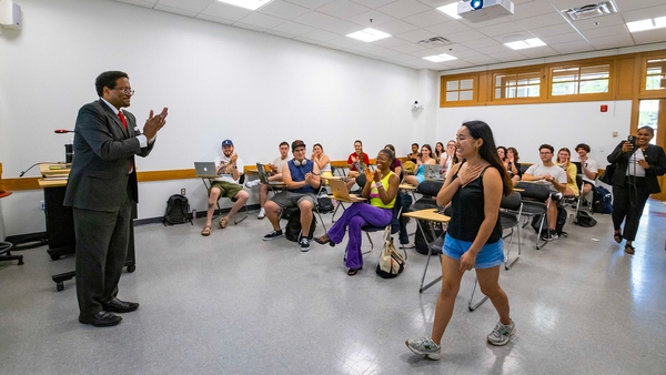 Michelle Wang walks to front of class as classmates and President Pines clap