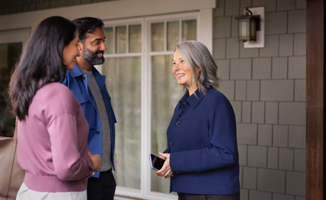 A couple talking to a real estate agent outside of a home