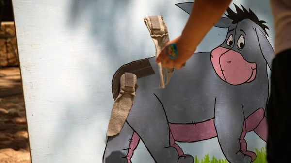 A partygoer attempts to pin the tail on Eeyore at the annual birthday party. 