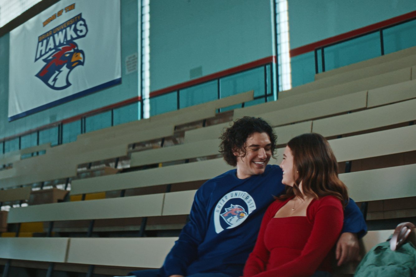 A still of characters Garrett & Hannah sitting in the stands outside of a hockey rink, from the Prime Video romance series Off Campus 