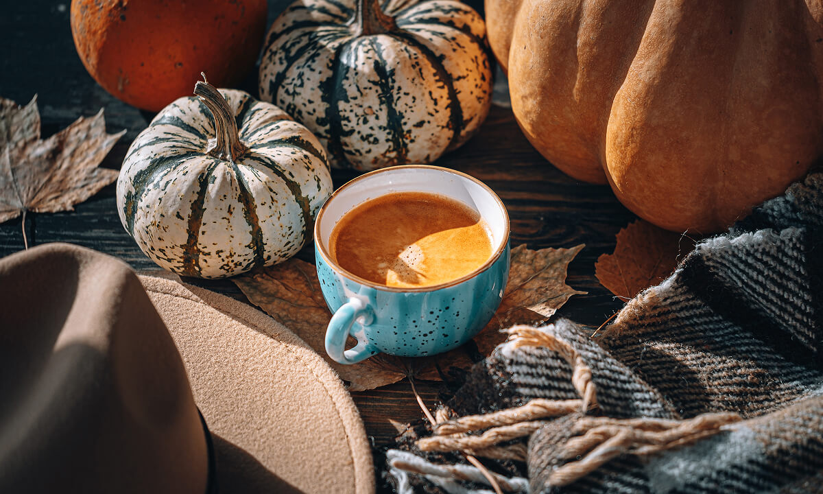 Coffee in a blue mug surrounded by pumpkins.