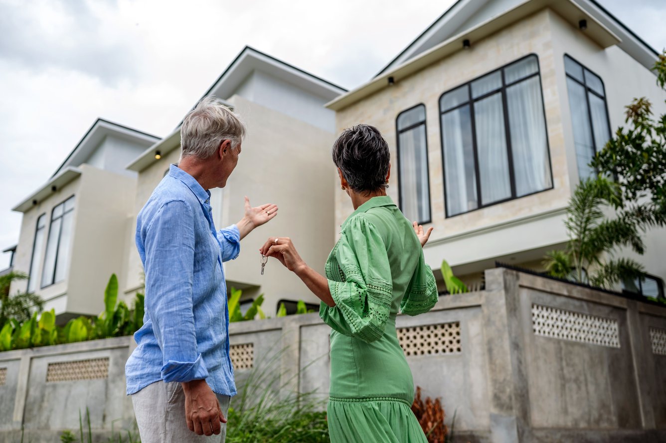 two seniors looking at the exterior of a home