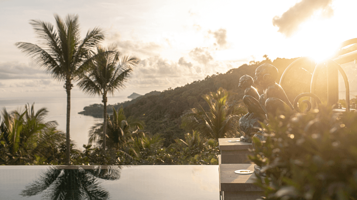 An outdoor area overlooking water and hills in the distance at sunrise.