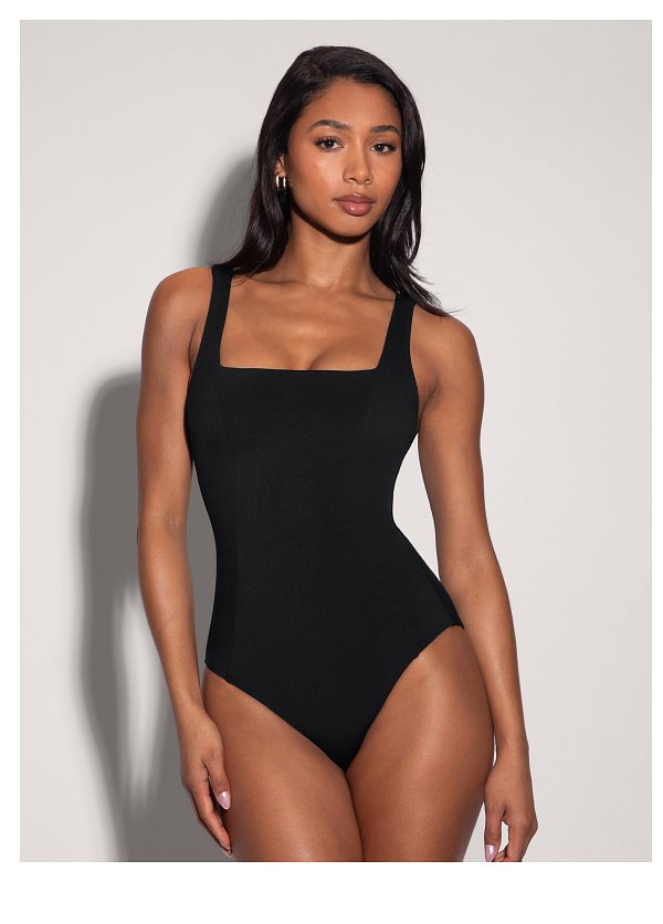 Model wearing a black one-piece swimsuit, standing against a neutral background.