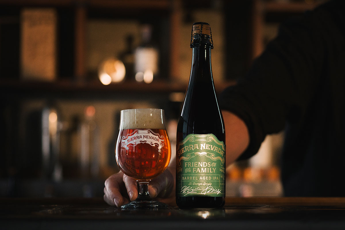 A bartender presenting a glass of Barrel-Aged Ruthless Rye IPA next to its bottle