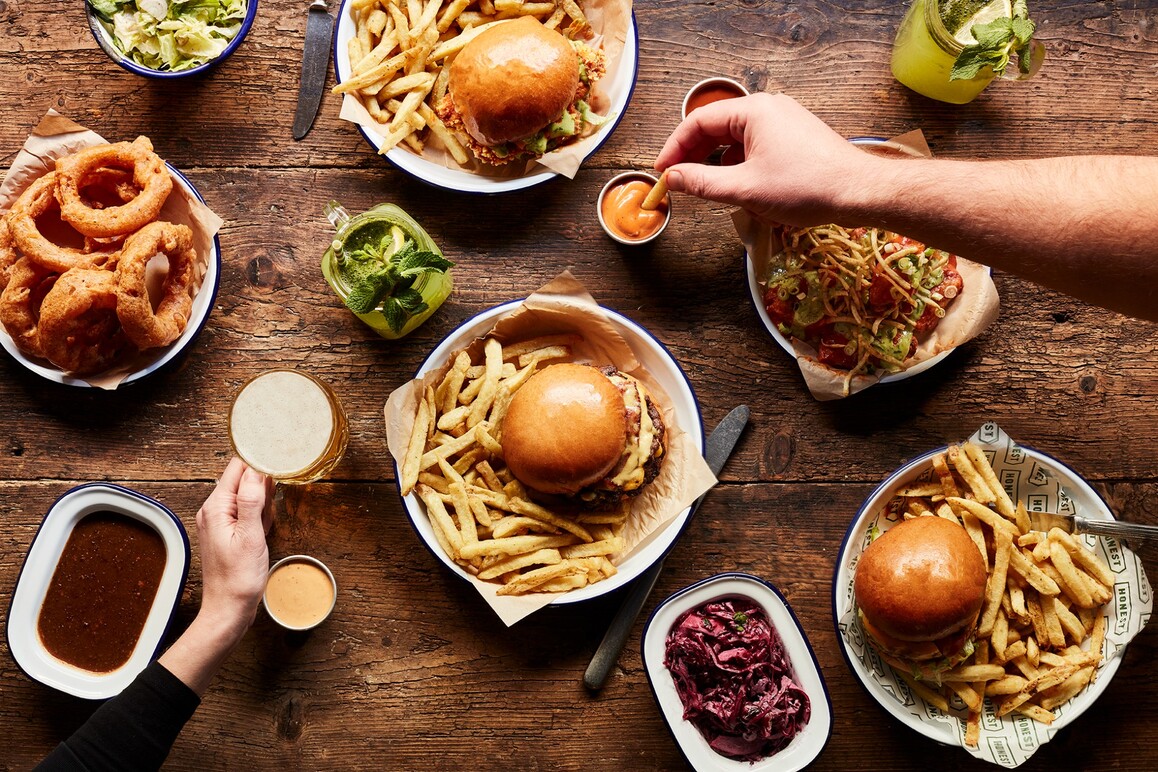 Burger spread on table with hands