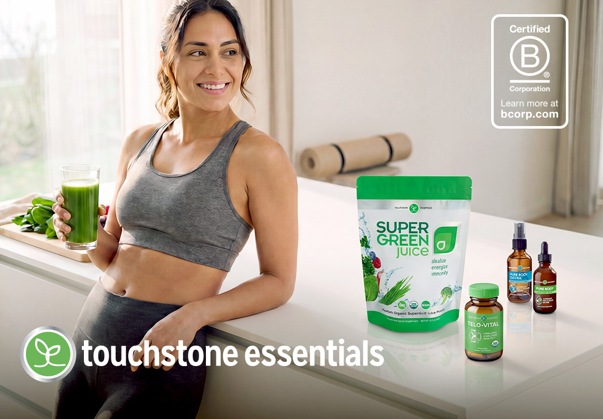 Woman holding green juice with supplements on counter.