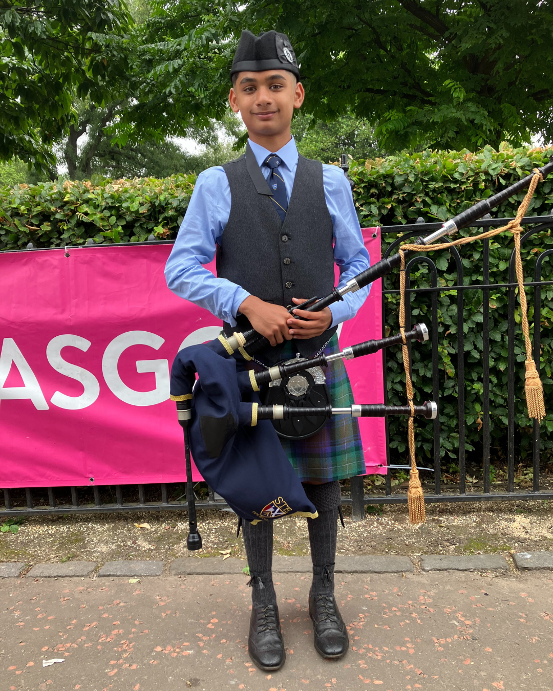A medium-skinned teenage boy wearing a traditional Scottish kilt and holding a bagpipe