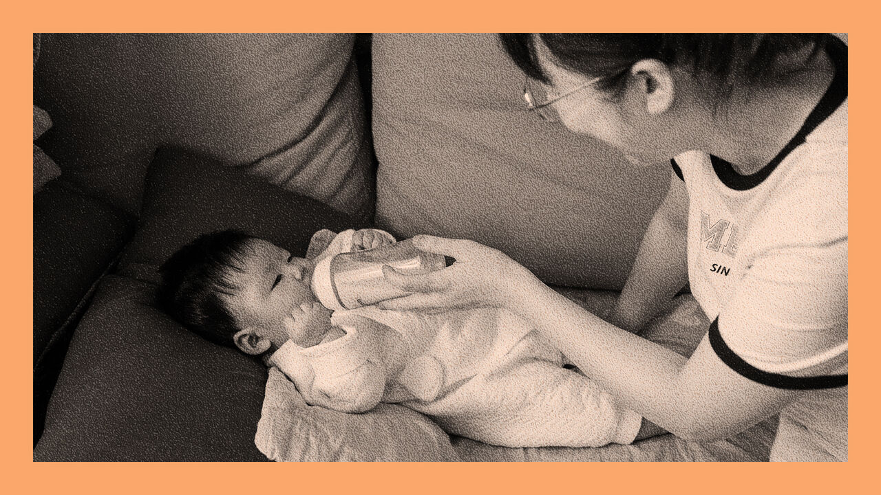 A young mother feeds her baby with a bottle whilst they lay on the sofa in Luannan County, China.
