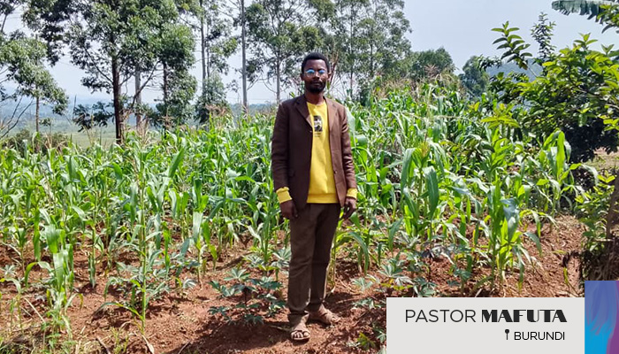 Pastor Mafuta standing in a field of crops.