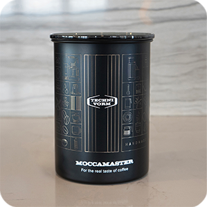 A matte black coffee canister with a custom Moccamaster design.