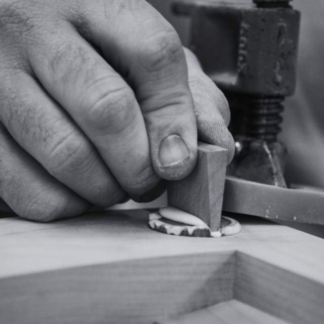 A hand holds a wedged tenon in place.
