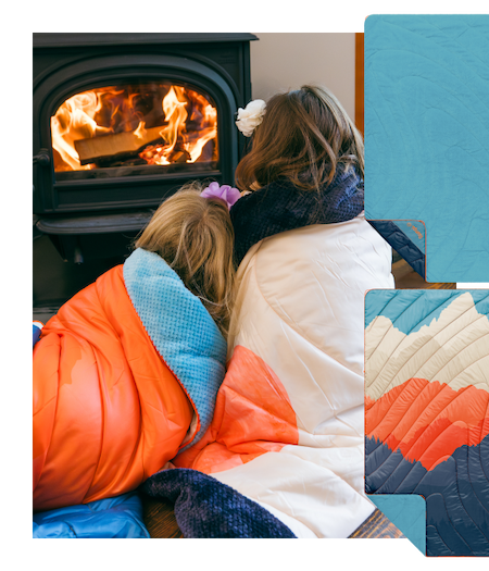 Two kids wrapped in fleece puffy blankets, staying warm in front of a wood stove