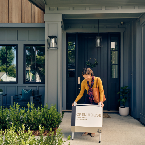 Woman adding open house sign outside home