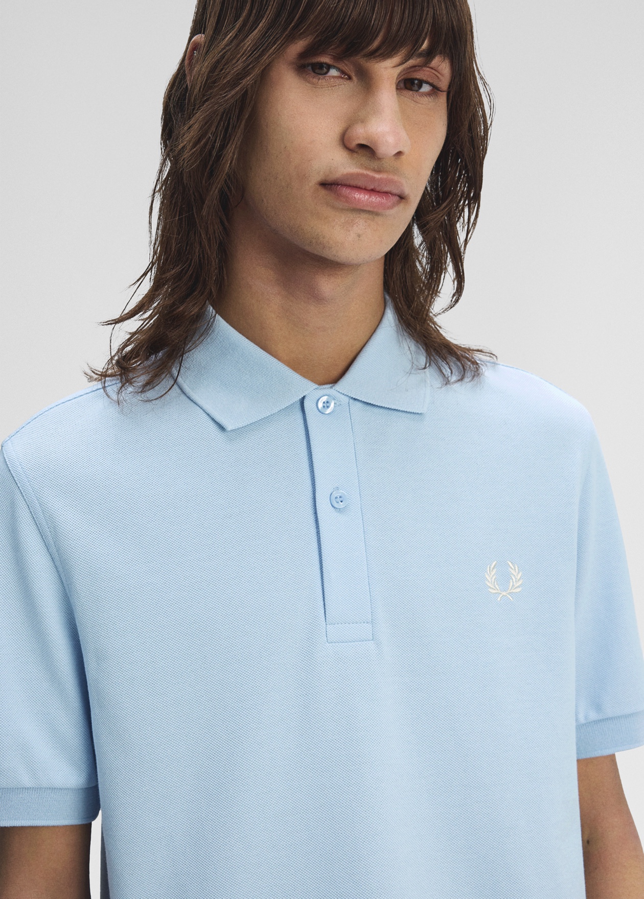 Male model wearing a one-colour Fred Perry polo in pale blue