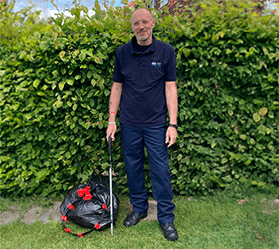 Paul, an RSPCA Wildlife Friend, stands on grass with a litter picker and a bag of litter