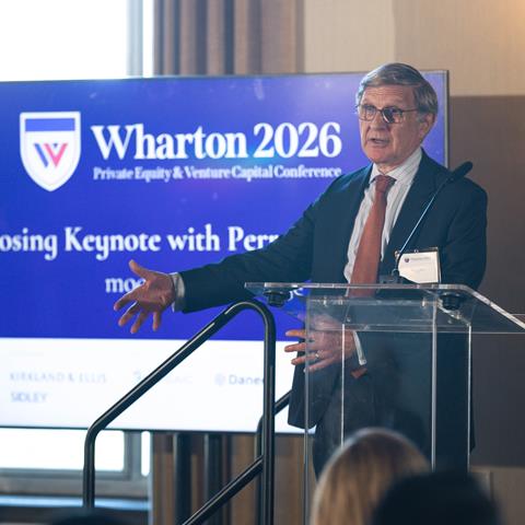 A person speaks at a podium before a banner with the headline "Wharton 2026"