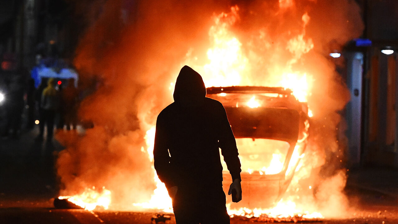 A vehicle burns as PSNI riot squad officers battled protesters throwing projectiles in Ballymena.
