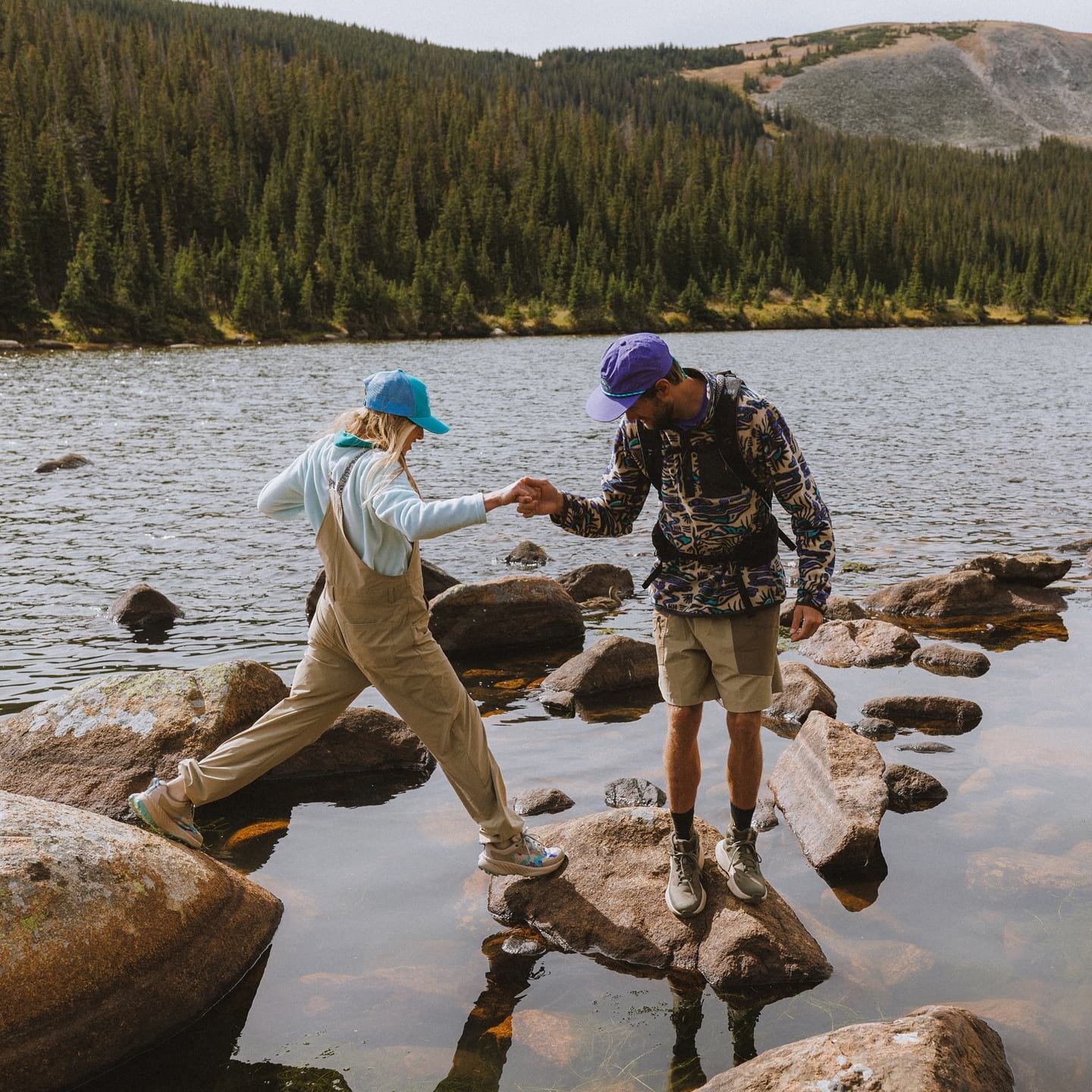 Two hikers in Helly Hansen gear on the shore of a lake