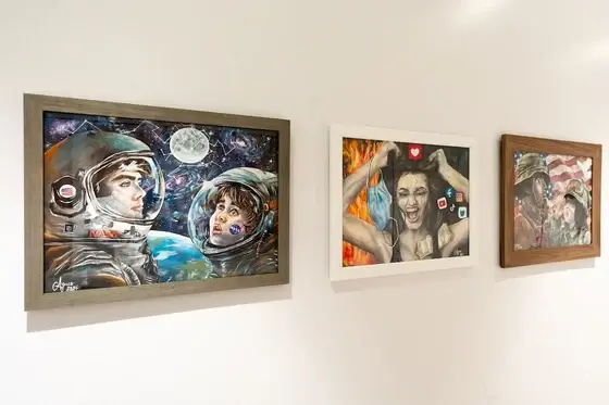 Three pieces of artwork hang on a white wall.