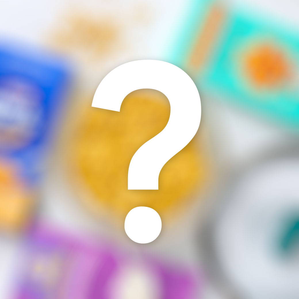 Blurred background of colorful food packaging and ingredients with a large white question mark in the center, suggesting a mystery or surprise recipe reveal.