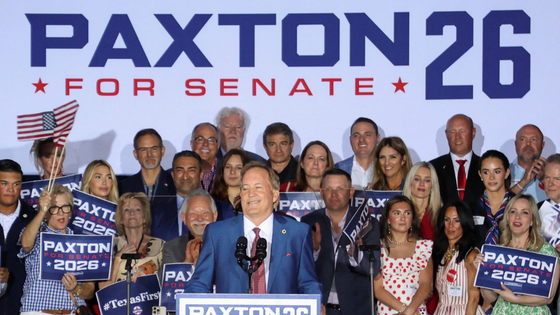 A man speaks at a podium behind a sign reading 