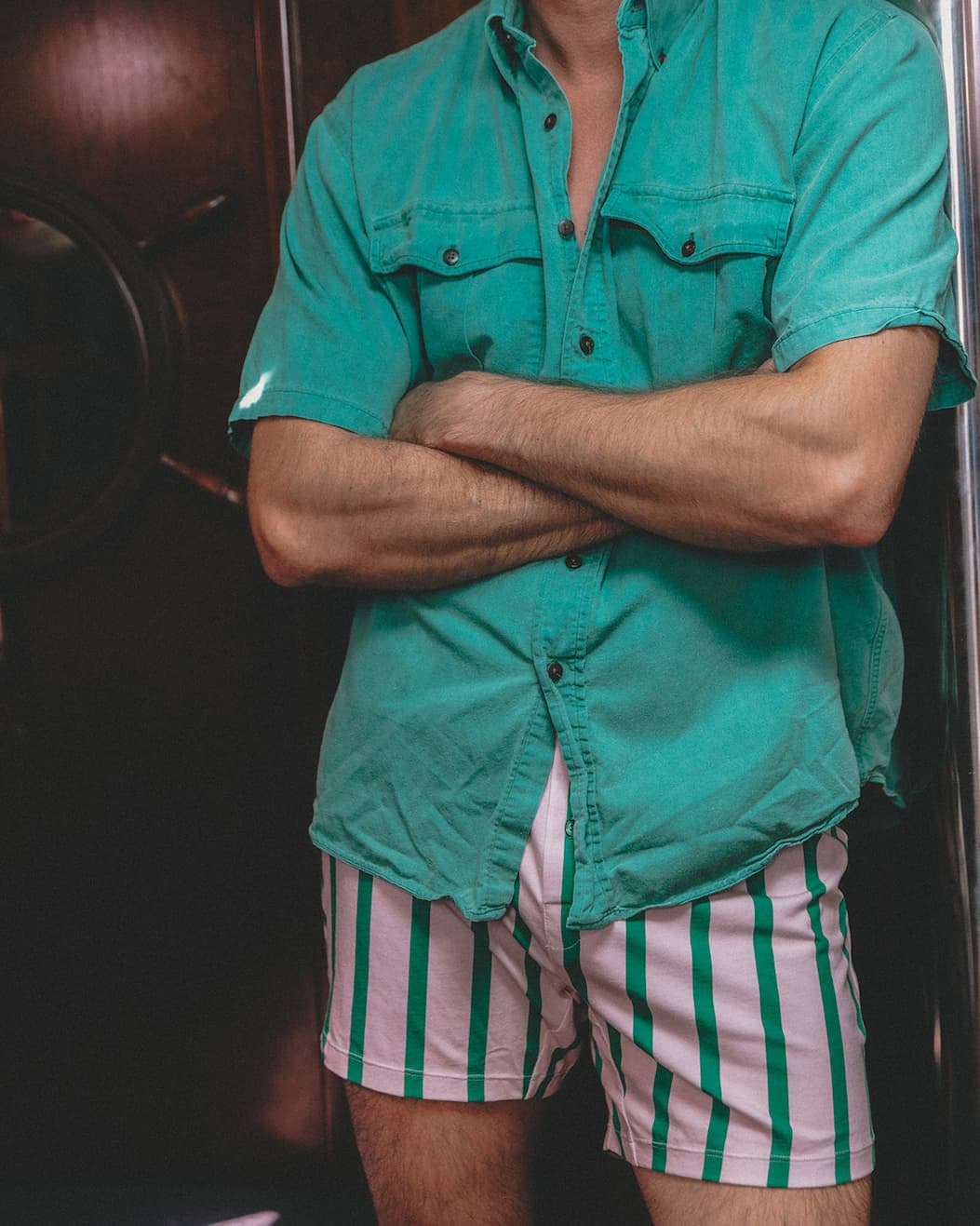 Man standing in boat wearing green shirt and pink/green stripe slim fit boxers