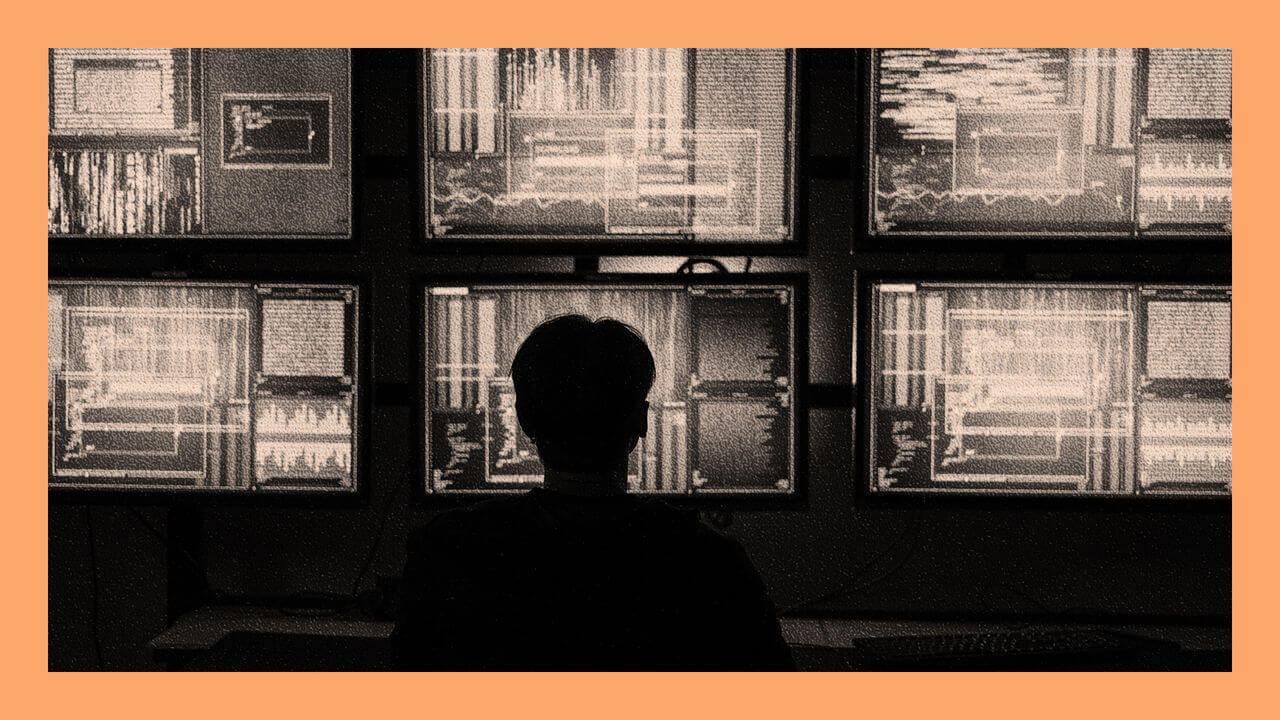 Hacker with Covered Face in His Operating Room with Multiple Displays