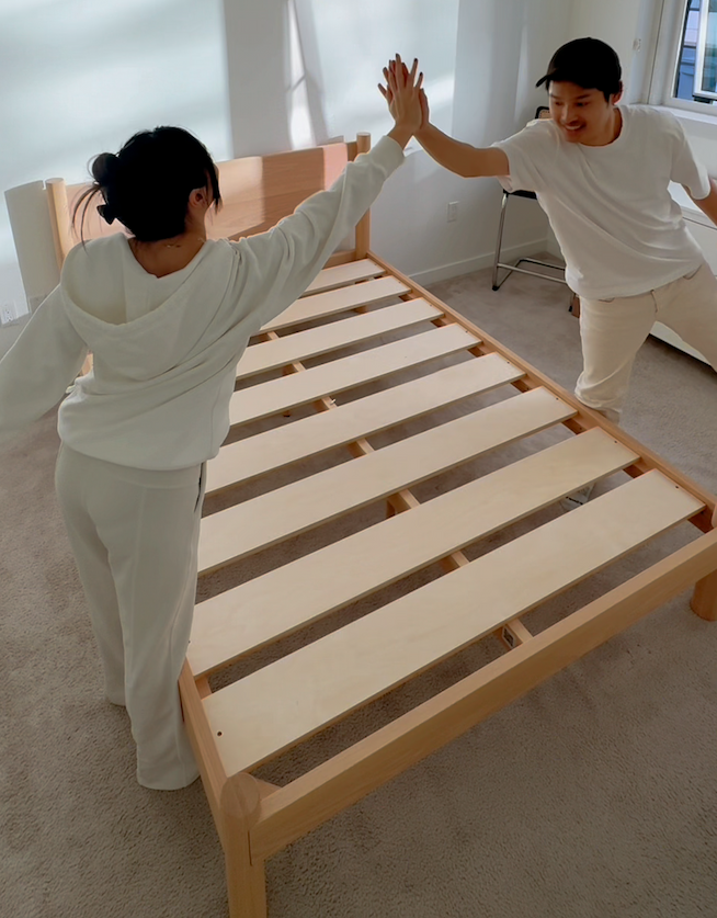 Two Keeps customers high-fiving after easily assembling their Architect Bed in natural in white bedroom