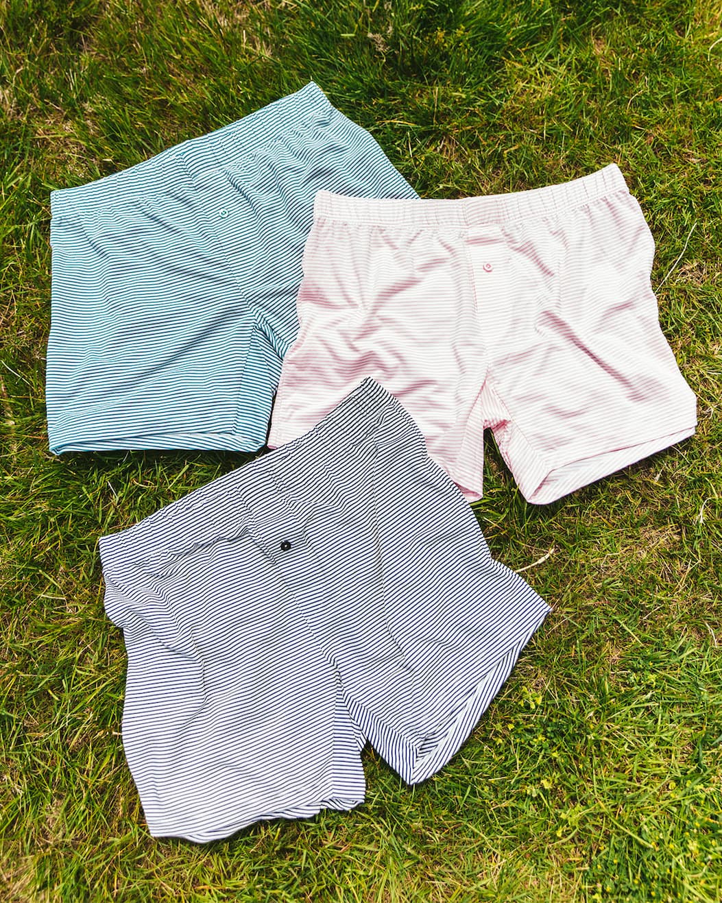 Three pairs of tech varsity slim fit boxers (blue pink and green) laying on the grass