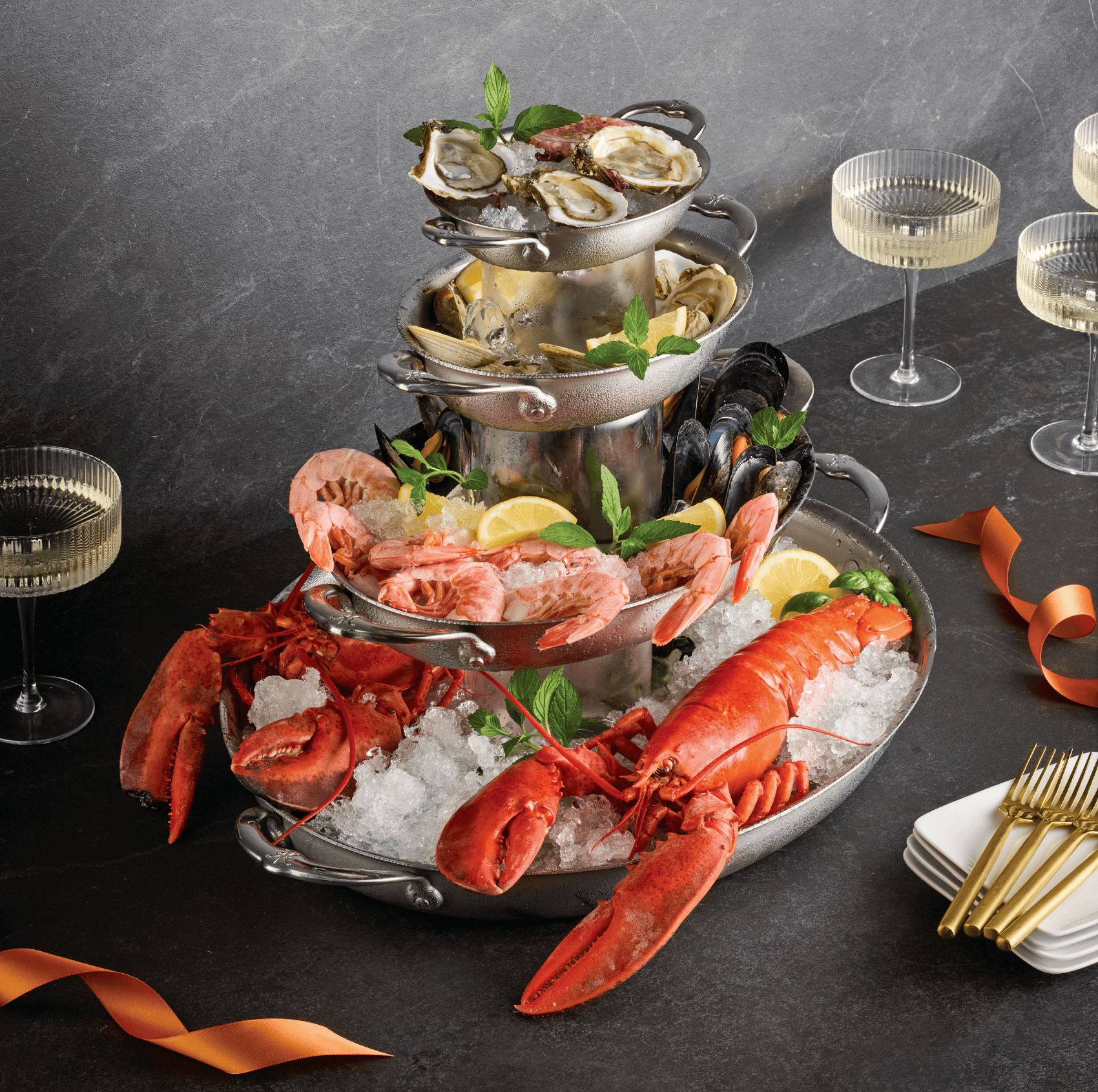 Happy New Year. A Festive New Year Seafood Tower is photographed on a dark marble counter with Oysters, Lobster, Shrimp and Boiled Clams. Champagne? Of Course.