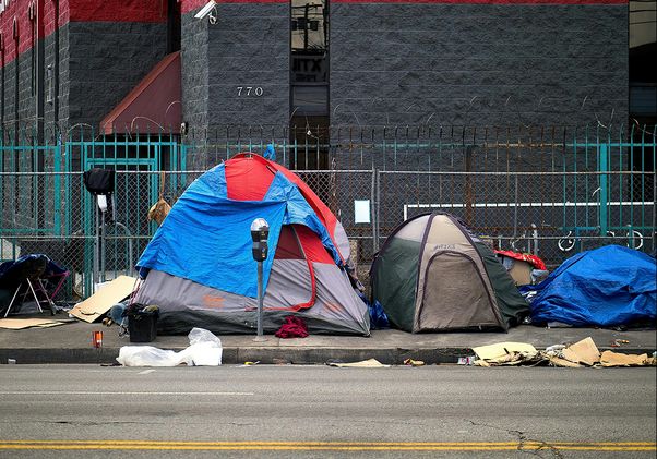 Group of tents on sidewalk with barbed wire fence behind
