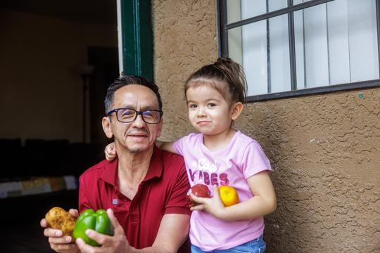 Pedro and his daughter holding produce.