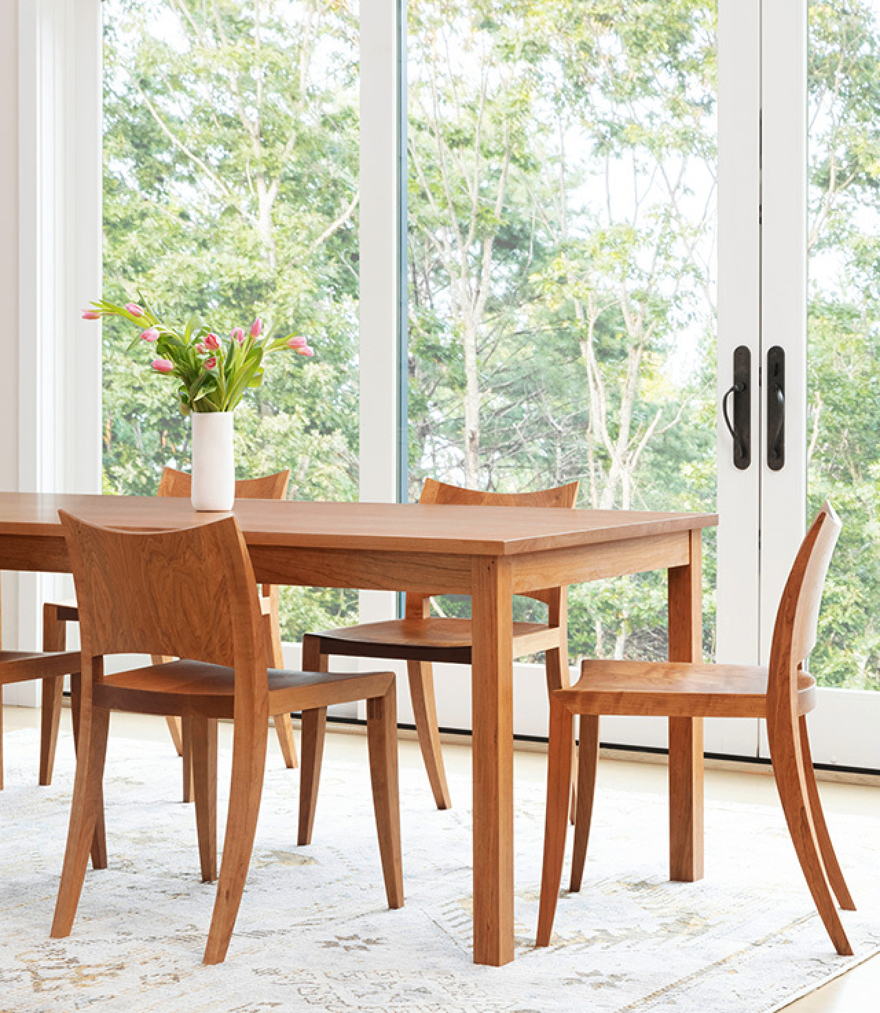 The Eastward Table and several Auburn Chairs in front of a large wall of windows.