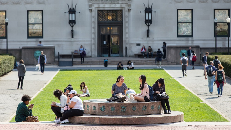 Students sitting on the sundial with Butler Library in the background