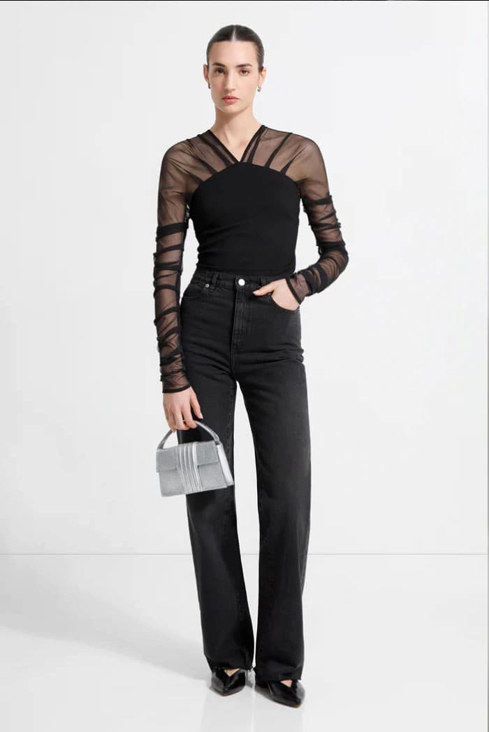 A full-length view shows Emily in The Lita Top with high-waisted black jeans, pointed heels, and a small silver handbag.