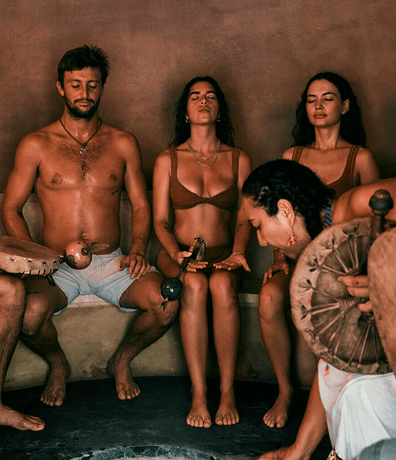 A group in a peaceful sauna session, seated in a dimly lit, cozy space.