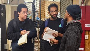 two people write in notebooks as they interview a third person