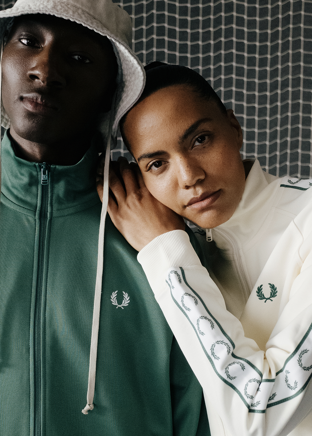 Close up of a male and female model wearing Fred Perry Contrast Tape Track Jackets in Ecru and Sport Green