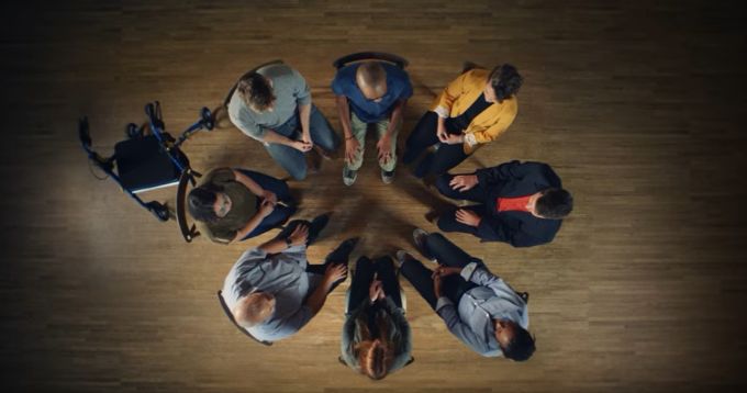 A group of people sit in chairs arranged in a circle.