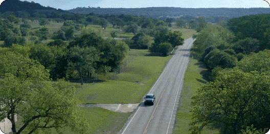 F-150 Lightning driving on a freeway surrounded by lush fields.