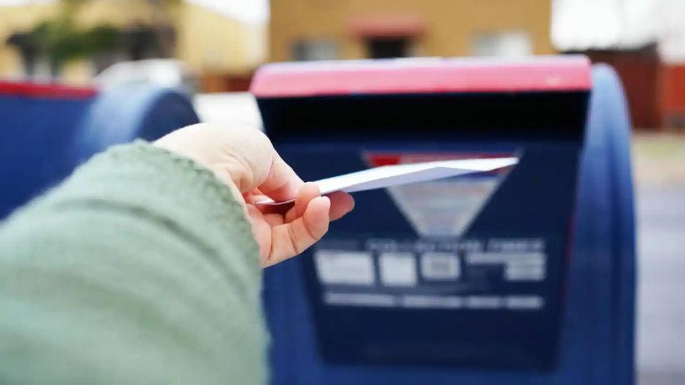 Image depicting someone placing their election ballot in the mail box.