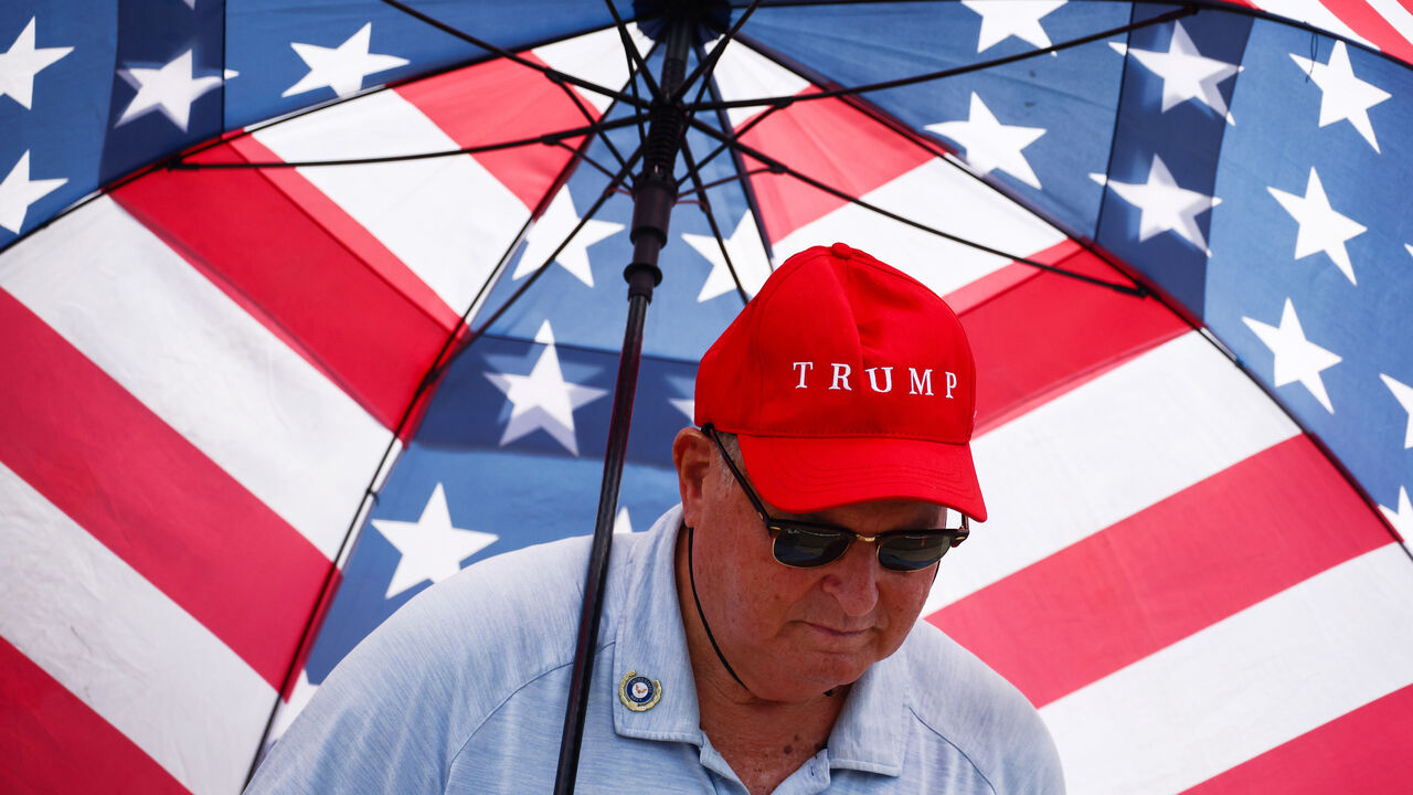 A Donald Trump supporter holds an umbrella with a US flag on.