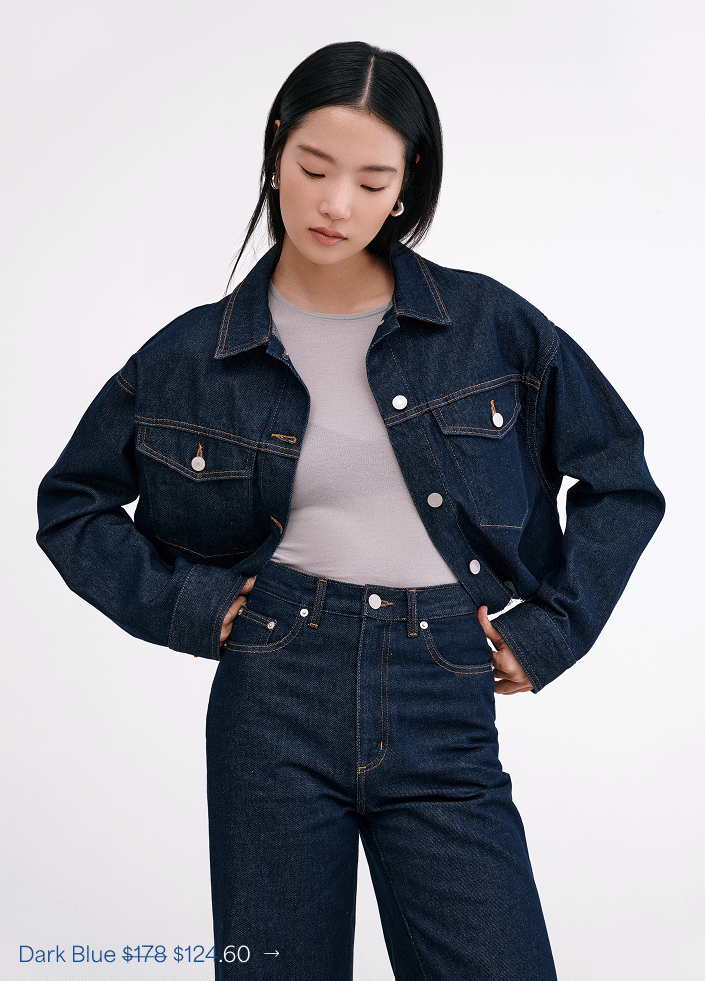 Xun in The Rockland Denim Jacket over a light gray tee with high-waisted dark denim jeans against a white studio backdrop.