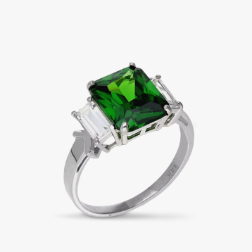 A green tourmaline emerald-cut three-stone ring on a gray tile.